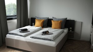 A neatly made bed with white linens, two gray pillows, and two mustard-colored pillows. - aparthotel glück auf Düppelstrasse (Oberhausen)