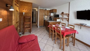 A compact living space with a kitchenette, a dining area, and a TV mounted on the wall. - Modern studio PMR, south balcony sleeps 4 - Montgenèvre (Montgenèvre)