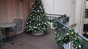 Un patio in legno con un albero di Natale, un tavolo in metallo e sedie.