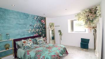 A bedroom with a bed, a large mirror, a window with flowers, and a patterned floor.
