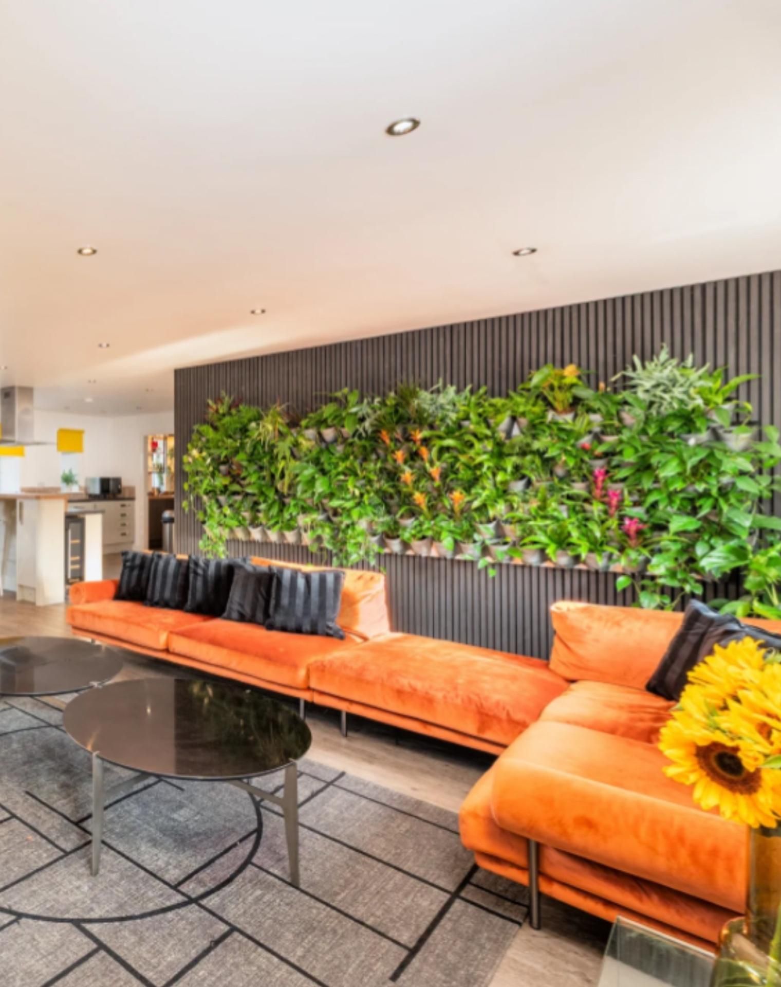 Un intérieur moderne avec un ensemble de canapés, une table basse et un jardin vertical.
