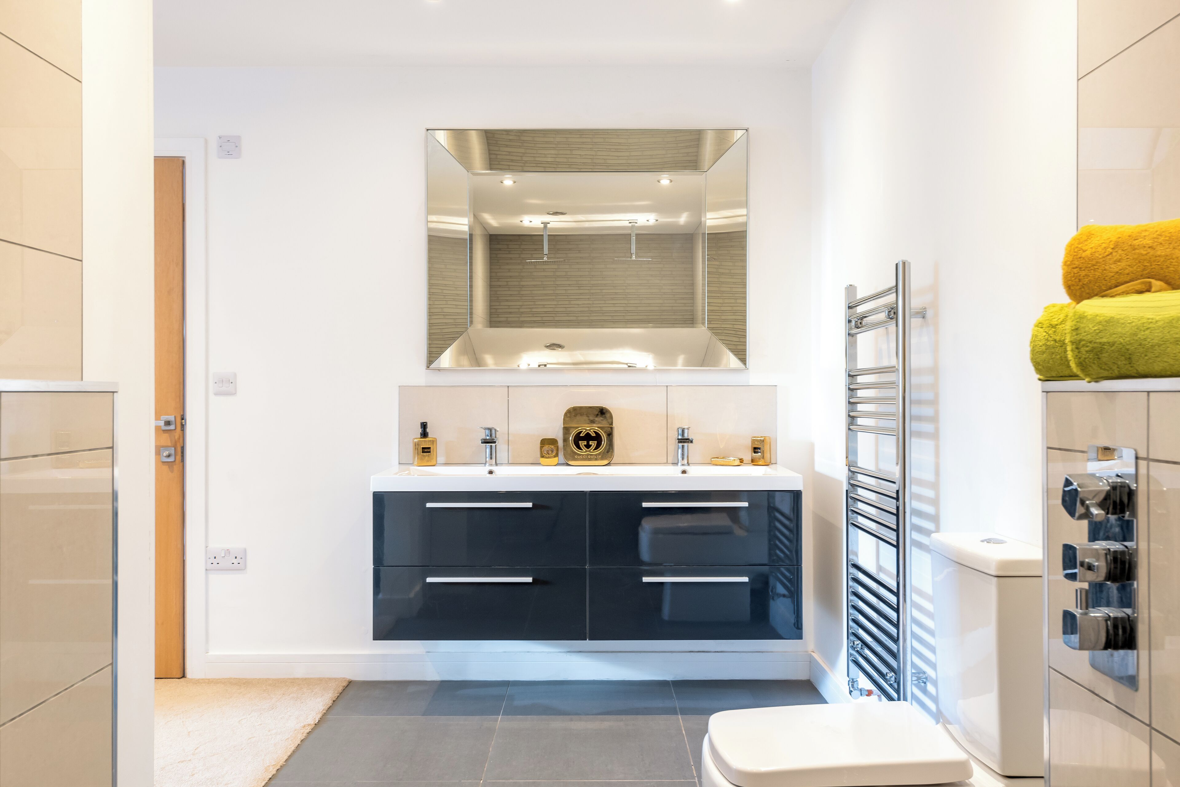 A modern bathroom with a large mirror, a double sink vanity, and a towel rack.