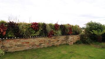 A brick wall with a variety of plants and shrubs.