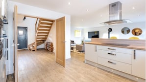 Une cuisine moderne avec un plancher en bois, une cuisinière encastrée et un grand îlot central doté d’un évier.