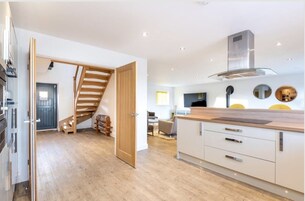 A modern kitchen with wooden flooring, a built-in stove, and a large island with a sink.