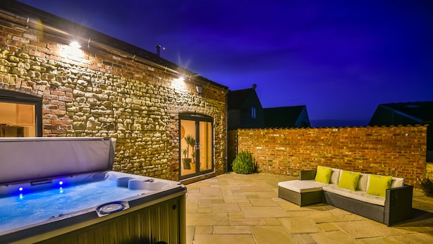Un bâtiment en pierre doté d’un jacuzzi et d’un espace extérieur aménagé pour s’asseoir.