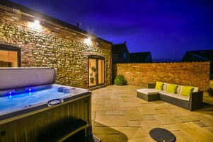 A stone building with a hot tub and outdoor seating area.