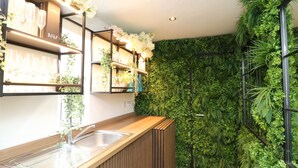 Une cuisine moderne avec des plans de travail en bois, un évier en acier inoxydable et des étagères où sont rangés des verres.