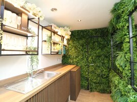 A modern kitchen with wooden countertops, a stainless steel sink, and shelves with glassware.
