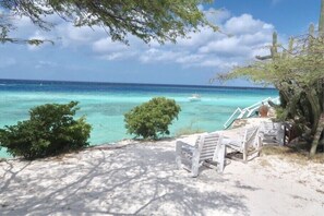 A beach with a wooden bench and a boat in the water.