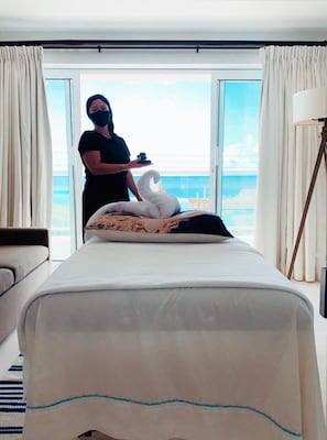 Ein Hotelzimmer mit Bett, Meerblick und einer Person, die am Fenster steht.