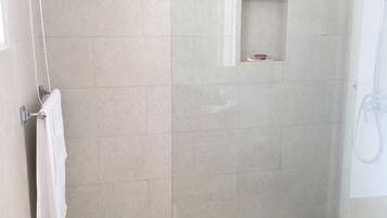 Un espace douche moderne doté d’une porte en verre, d’une petite étagère et d’un porte-serviettes.