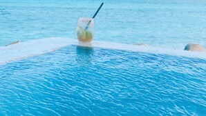 A pool with clear blue water and a drink on the edge.
