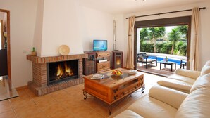 A living room with a fireplace, a television, a coffee table with apples, and a sofa.