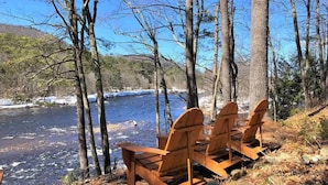 A river with a wooden bench facing the water, surrounded by trees. - Adirondack “River Rapture"- Lake George/Mount Gore (Warrensburg)