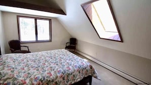 A bedroom with a bed, two chairs, a window, and a skylight. - Adirondack “River Rapture"- Lake George/Mount Gore (Warrensburg)