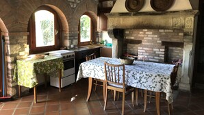 Una cocina rústica con un arco de piedra, una mesa de madera con mantel floral y una chimenea de ladrillo.