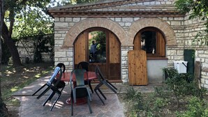Un edificio de piedra con puertas arqueadas y un pequeño patio con sillas y una mesa.