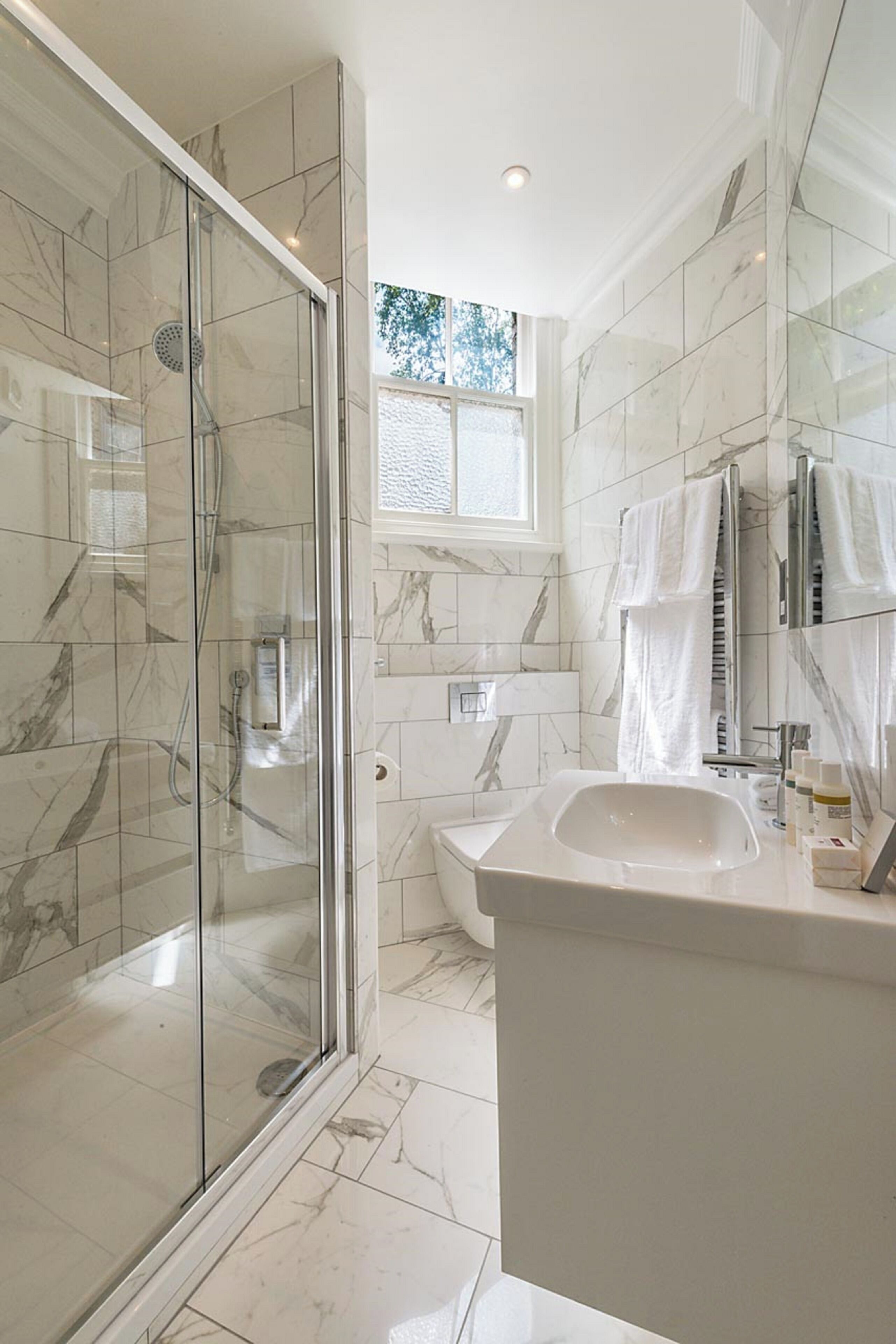 A modern bathroom with a glass-enclosed shower, a large sink, and a toilet.