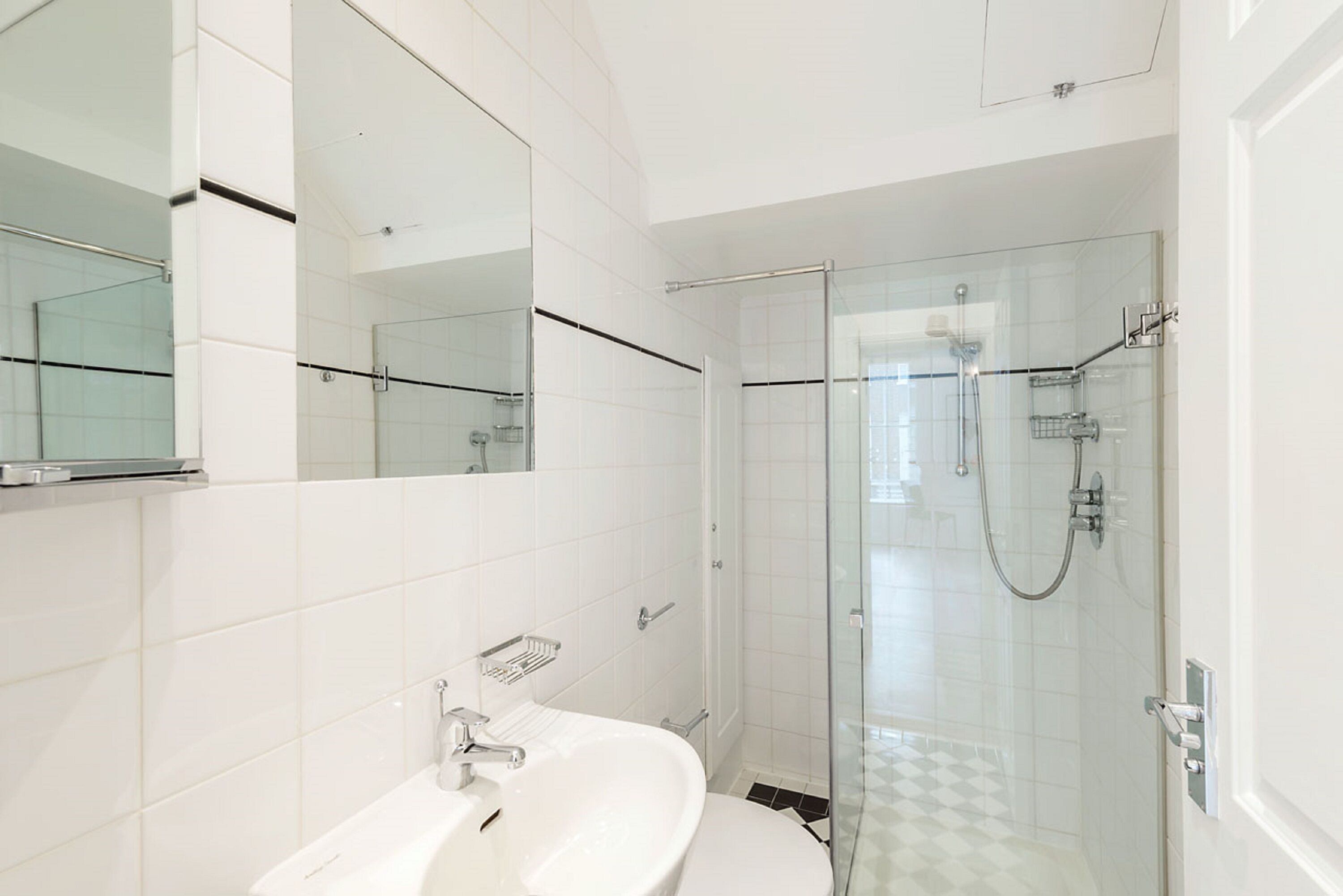 A modern bathroom with a glass-enclosed shower, a white sink, and a large mirror.