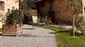 A courtyard with stone buildings, a gravel path, and a bench. - OAR Cottage (Garai)