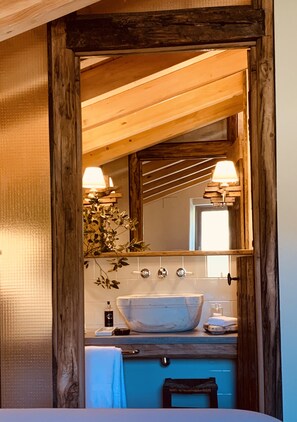 A bathroom with a wooden ceiling, a large mirror, a sink, and a towel rack. - OAR Cottage (Garai)