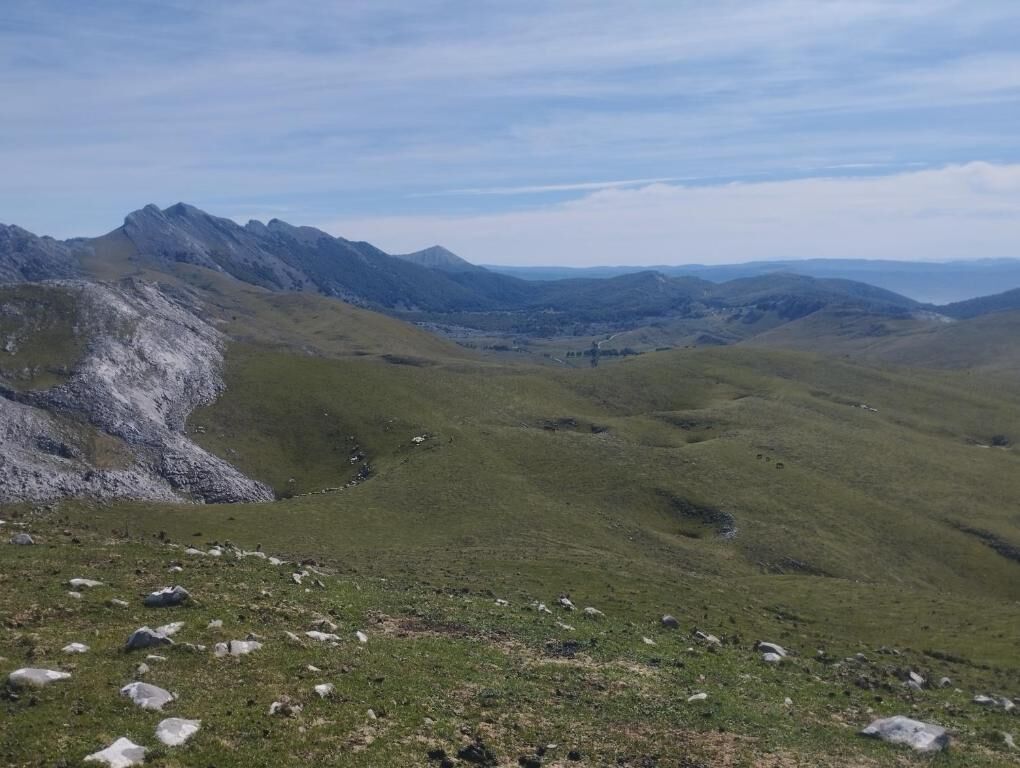 A mountainous landscape with a valley and distant peaks.