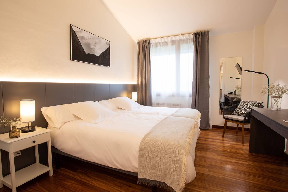Een moderne hotelkamer met een groot bed, nachtkastjes, een bureau en een stoel.