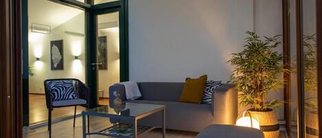 Una sala de estar moderna con un sofá, un sillón, una mesa de centro y una planta en maceta.