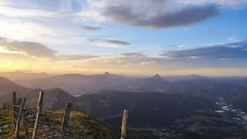 A mountainous landscape with a wooden fence in the foreground and a valley below.