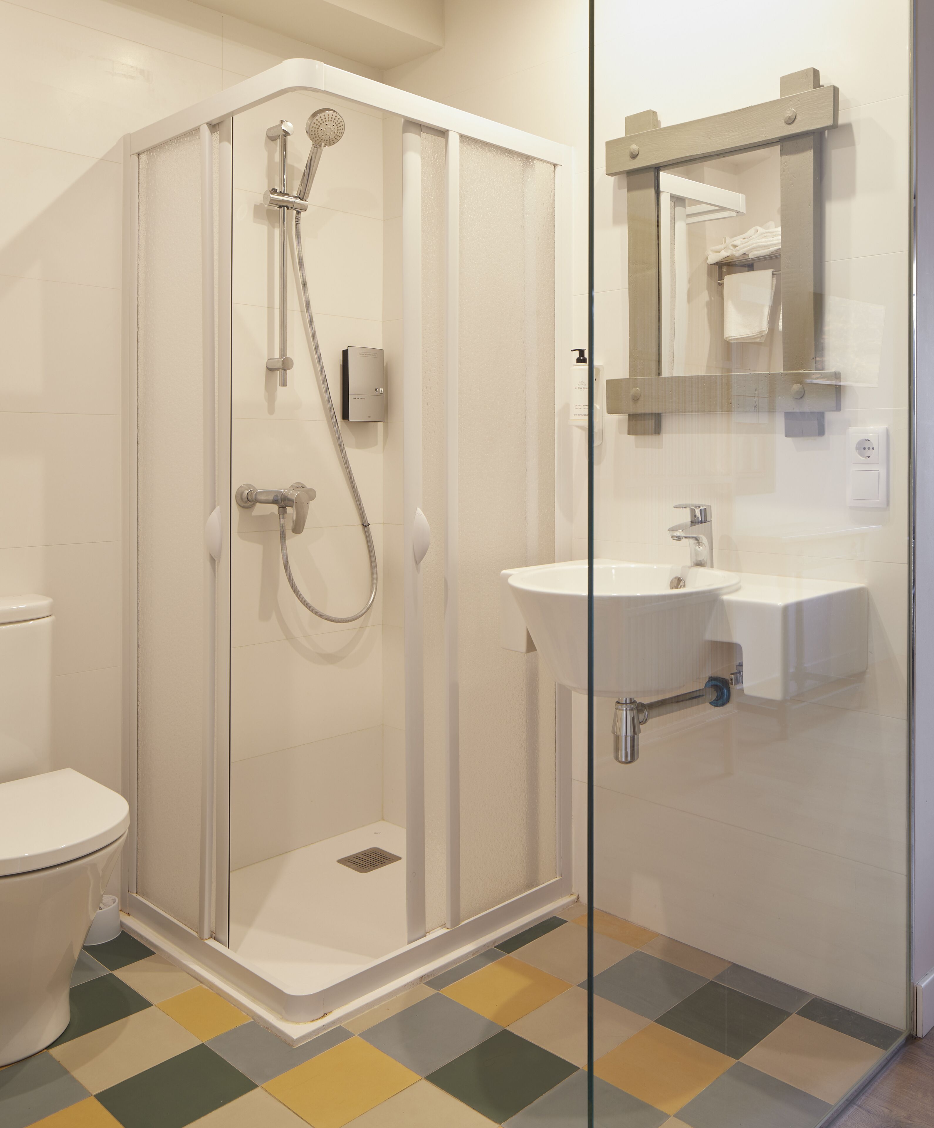 Un baño moderno con ducha de vidrio, lavamanos blanco y un inodoro.