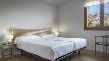 Camera d'albergo con un letto matrimoniale, comodini con lampade, una sedia e una finestra con vista sugli alberi.