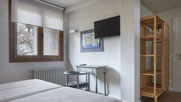 Un dormitorio con una cama, un escritorio, una silla, un televisor y una estantería de madera.