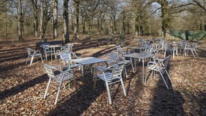 An outdoor seating area with metal tables and chairs, surrounded by trees. - Aritzalko (Etxarri-Aranatz)