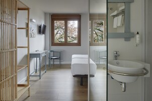 A modern bathroom with a sink, mirror, and window.