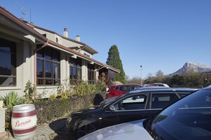 A building with a large barrel labeled "Beronia" in front, parked cars, and a mountain in the background.