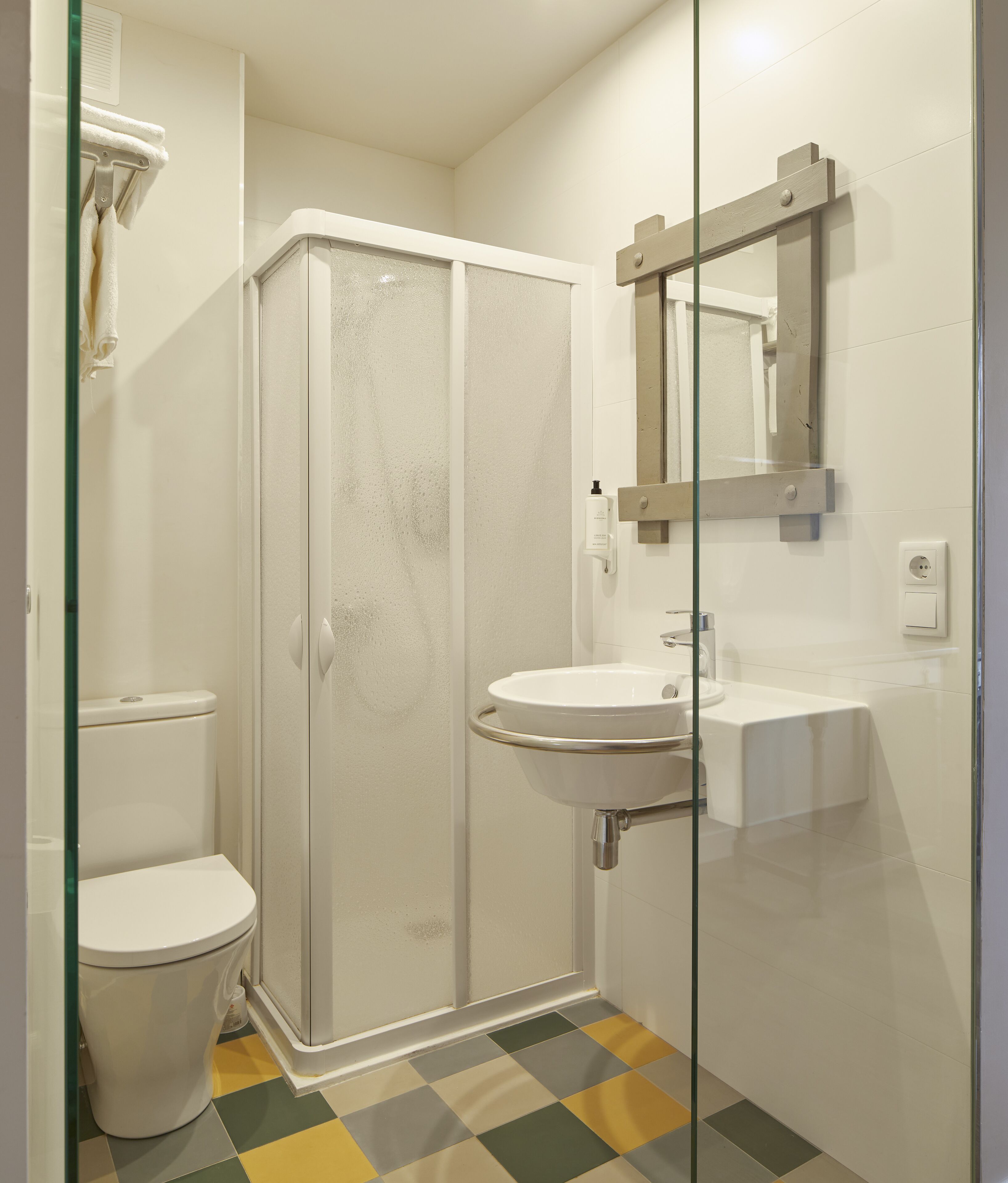 Une salle de bain avec une douche à parois de verre, un lavabo blanc et un miroir au-dessus du lavabo.