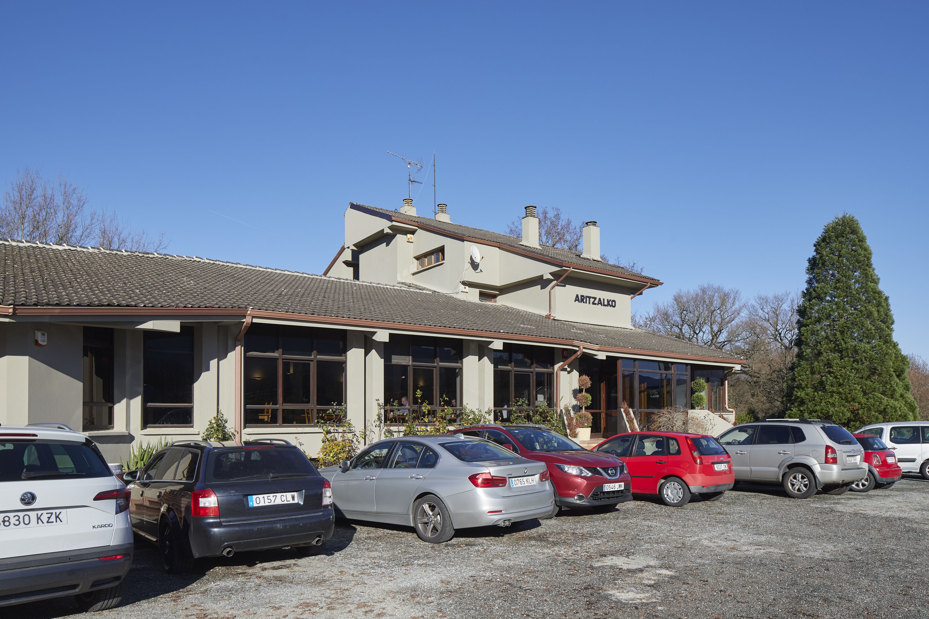 A building with a sign reading "ARITZALKO" and several parked cars in front.