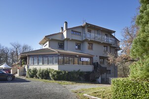 A multi-story building with a balcony on the upper floor, a covered entrance, and a visible sign indicating a business or service.