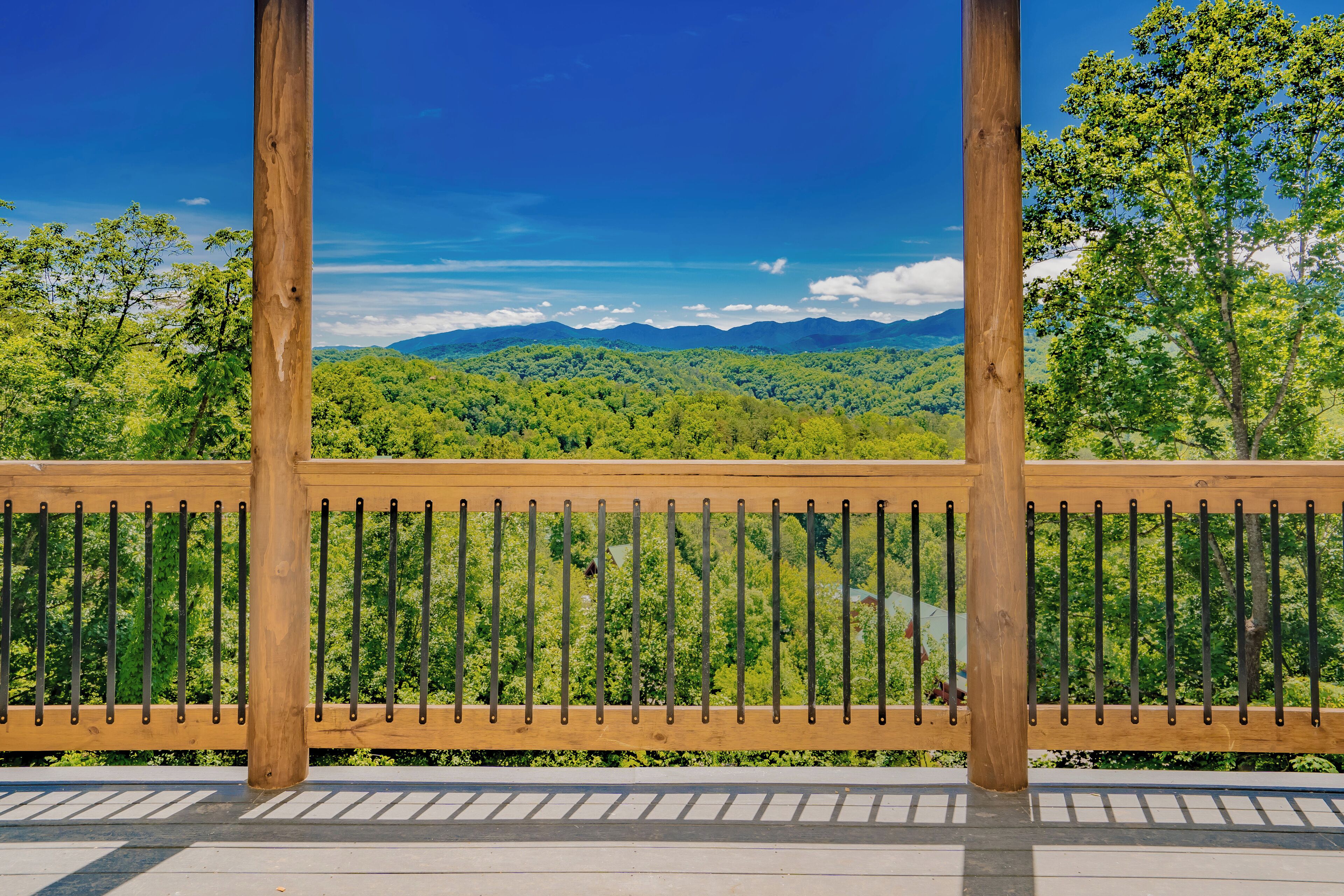 A wooden railing with a view of a forested mountain range.