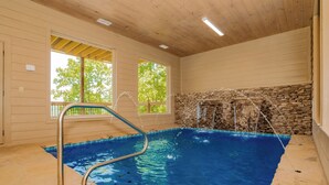 An indoor swimming pool with a stone wall and wooden ceiling. - Friendship Mtn Retreat: : Indoor Pool, Mtn View, Theater, Games, Hot Tub, Wifi (Pigeon Forge)