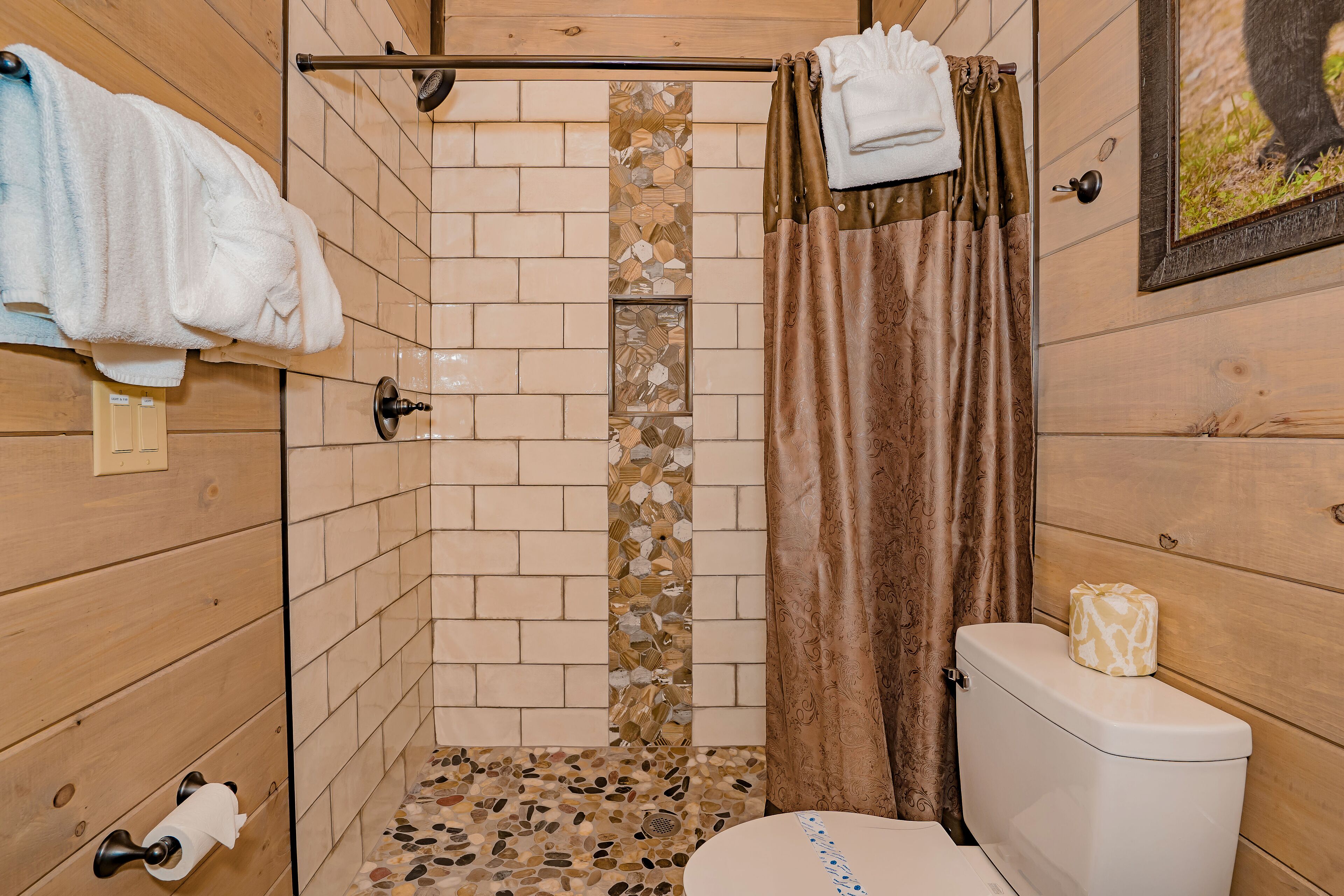 A bathroom with a shower, toilet, and towel rack.