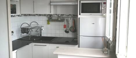 Una cocina compacta con gabinetes blancos, un microondas y un lavabo.