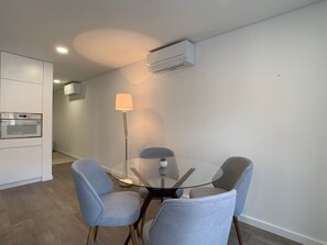 Een moderne keuken met inbouwapparatuur, een ronde glazen tafel met vier stoelen en een vloerlamp.