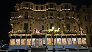 Een hotel met een statig gevel, meerdere balkons en een kerstboomdecoratie.