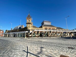 A public square with a clock tower, a covered walkway, and a building with a dome.