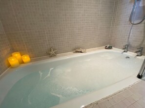 A bathtub with three candles, a starfish decoration, and a shower head.
