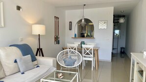 A modern living room with a sofa, a glass coffee table, and a dining area with chairs and a table. - Townhouse with sea view walking distance to the beach - 1 (Mijas Costa)