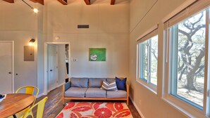 Una habitación acogedora con un sofá, una mesa de comedor con sillas y un ventanal con vistas a un árbol.