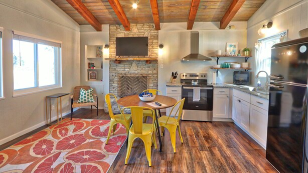 Una cocina con vigas de madera, chimenea de piedra y electrodomésticos modernos.